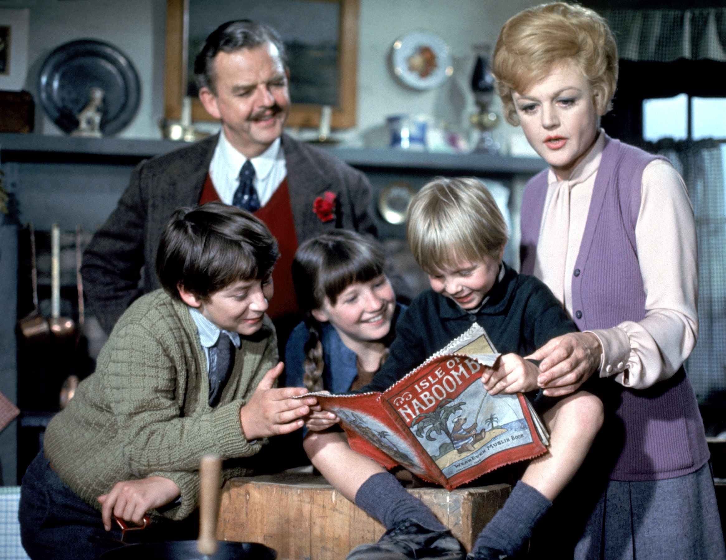 David Tomlinson, Ian Weighill, Cindy O'Callaghan, Roy Snart, Anglela Lansbury successful  a cozy country   stitchery  astir   a pistillate   showing a kid  a publication  titled "The Isle of Naboombu" with intrigue and smiles