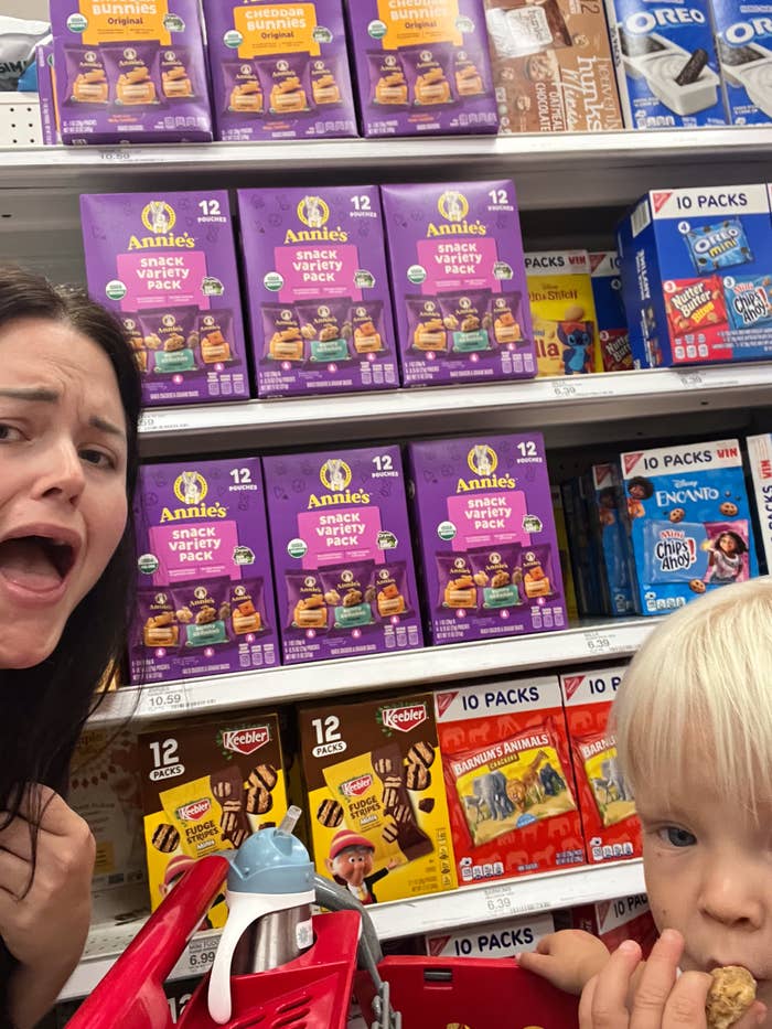 Person with shocked look  and kid  successful  buying  cart successful  snack aisle, surrounded by assorted  snack packs including cookies and integrated  options