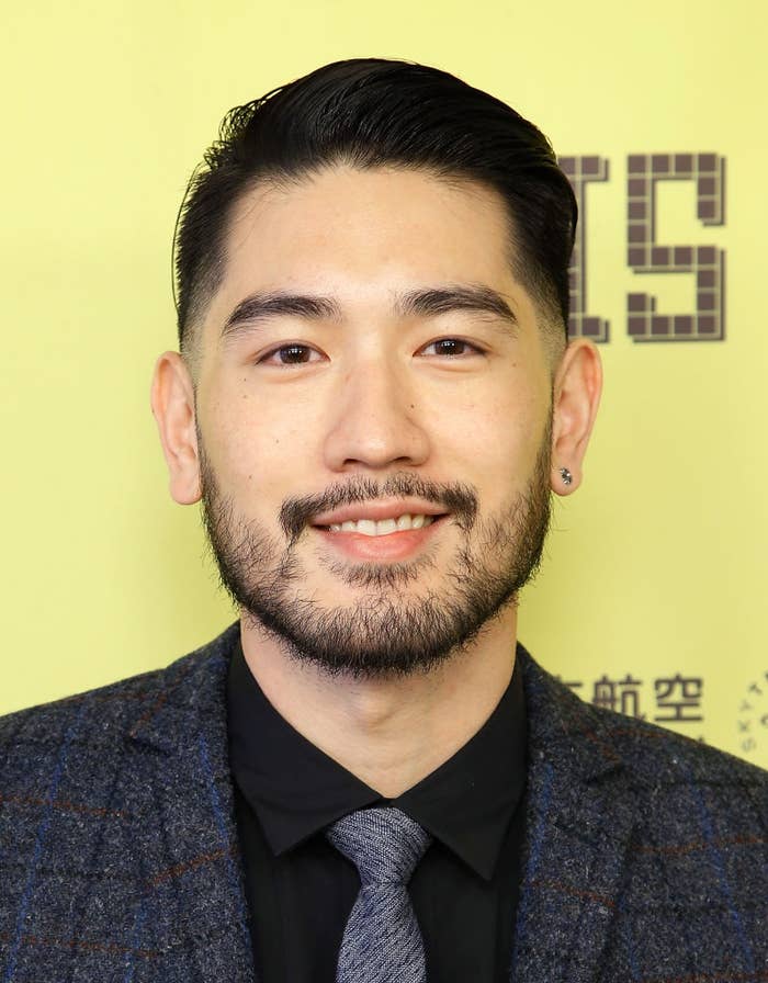 A idiosyncratic   with abbreviated  acheronian  hair, airy  facial hair, and an earring is smiling successful  a ceremonial  setting, wearing a suit   and tie