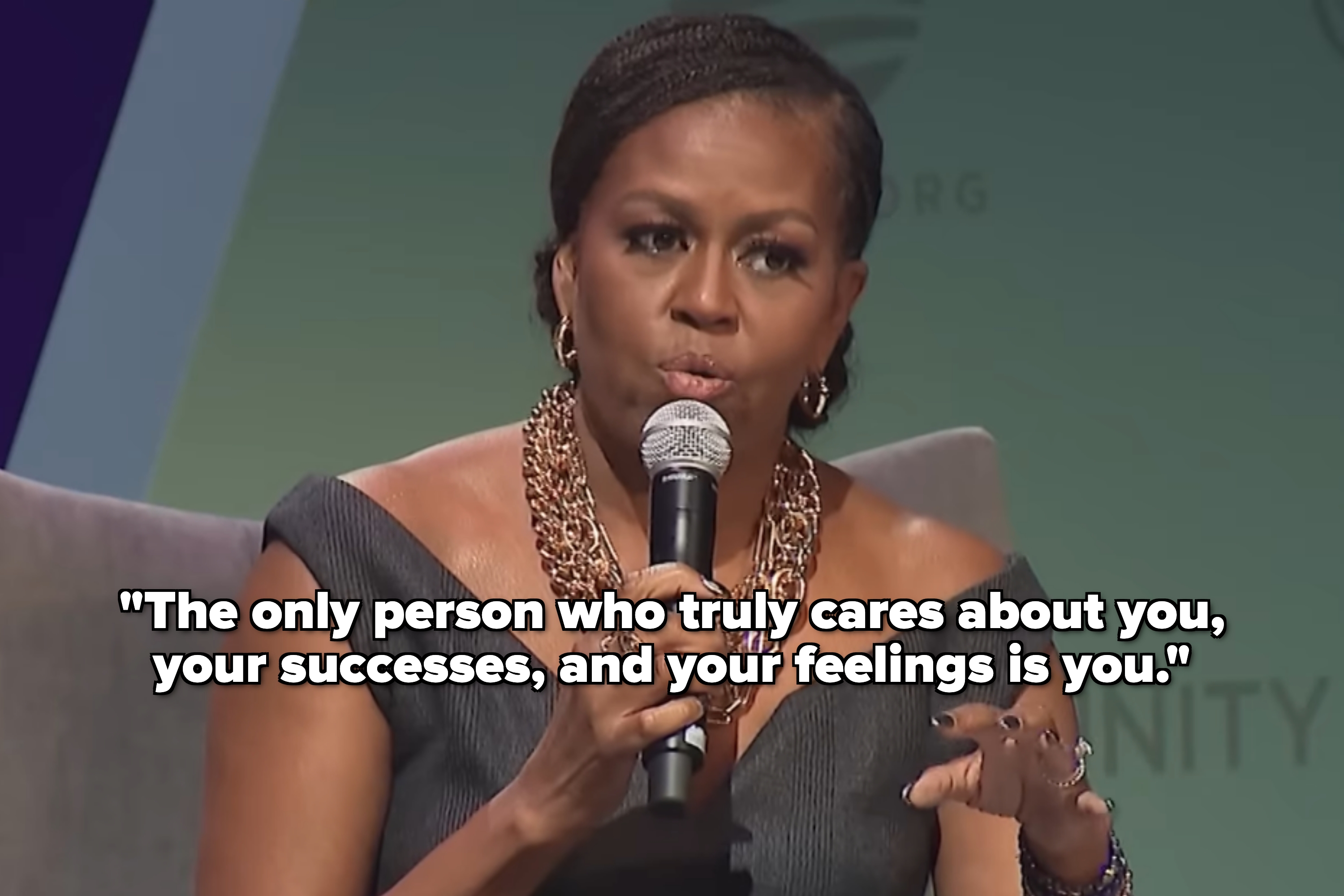 Person speaking into a microphone, wearing a stylish off-the-shoulder outfit and statement necklace, with a quote about self-care