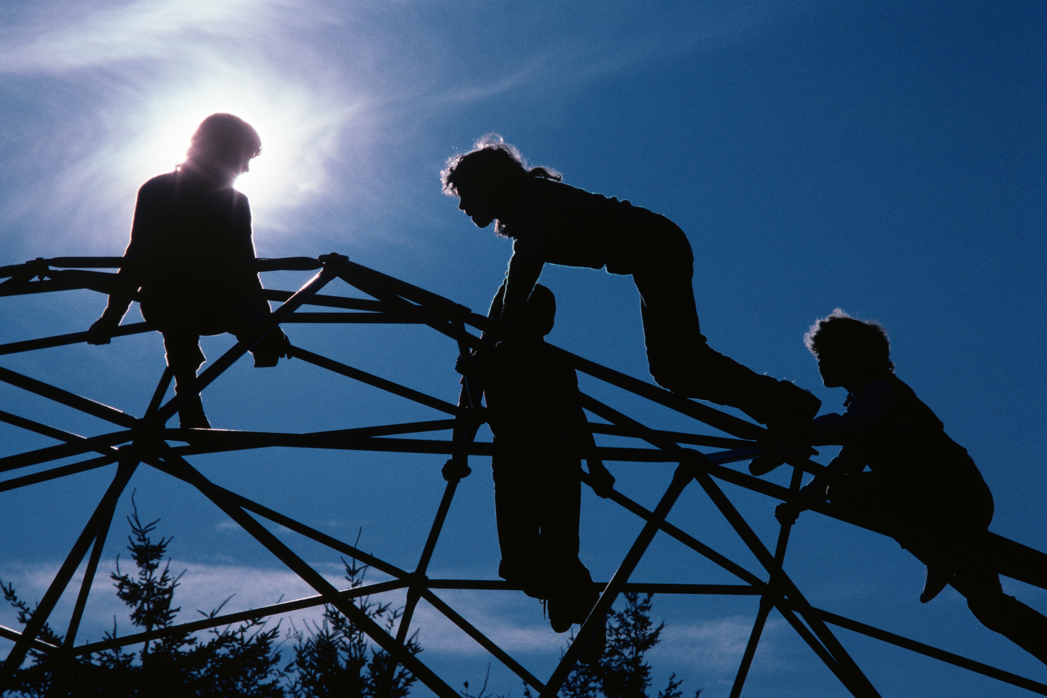 Silhouettes of children climbing connected a playground dome operation with the prima mounting down them