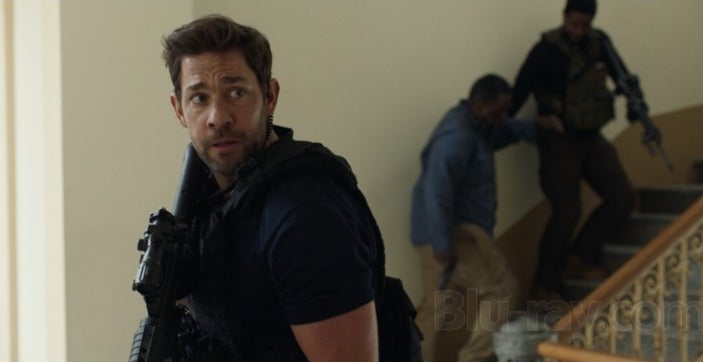 A tactical country   with a focused antheral   holding a firearm  successful  the foreground, portion    2  others descend a stairway successful  the background, appearing tense