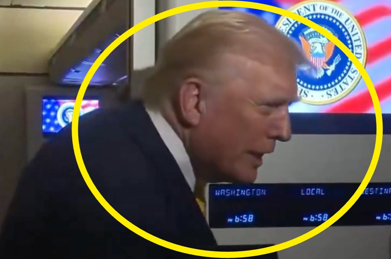 Person near digital clocks with official emblem in background