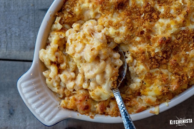 Creamy baked mac and cheese in a casserole dish with a silver serving spoon