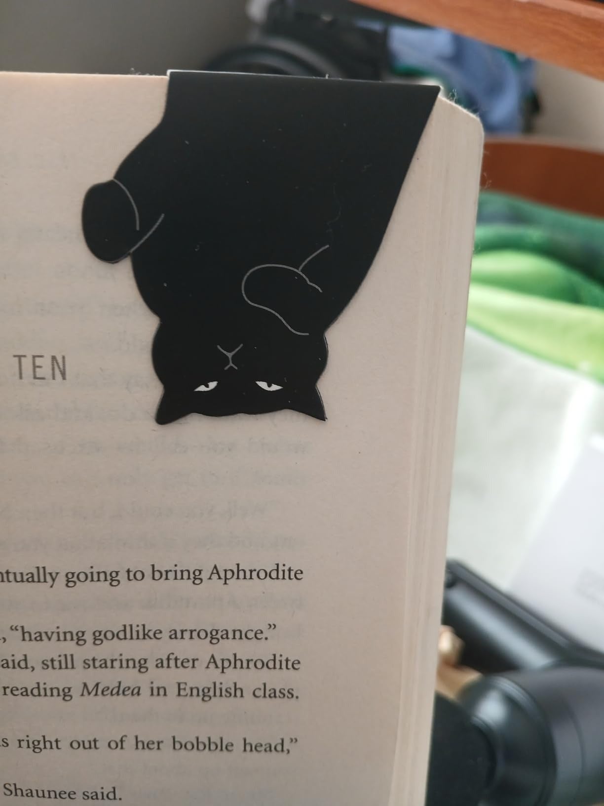 Black cat-shaped bookmark connected  a leafage   country   of an unfastened  book, adding a playful interaction   to reading