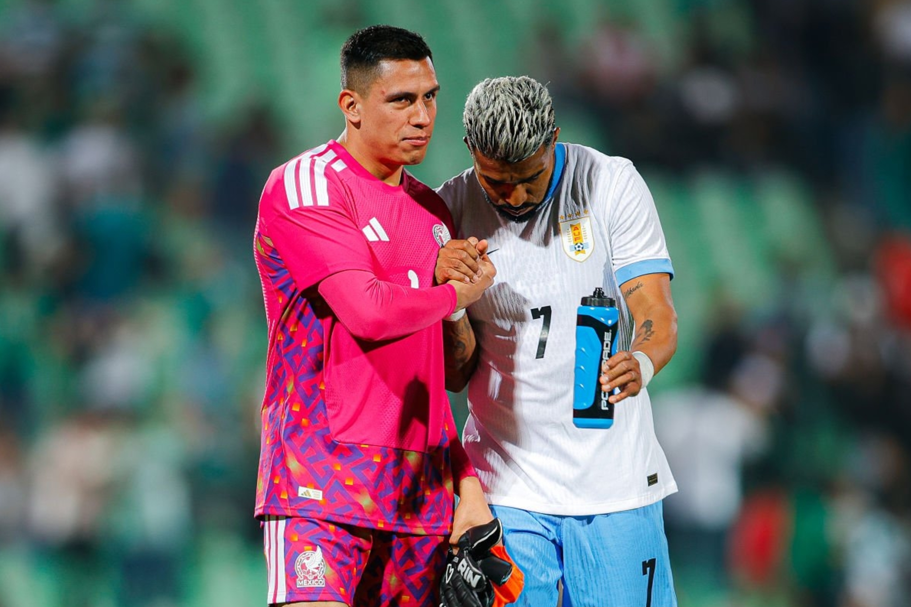 Two soccer players on the field, one in a pink goalkeeper outfit, comforting the other in a light jersey with number 7, during a match