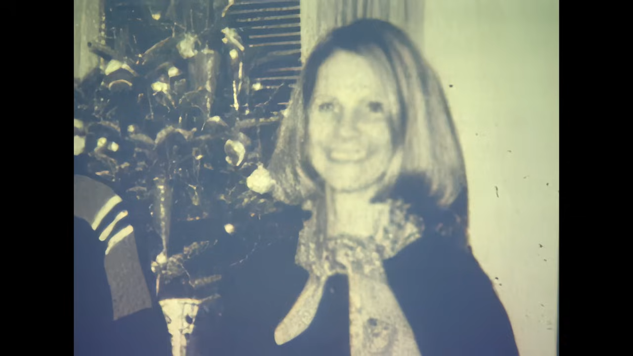 A vintage-style photograph  of a smiling pistillate   with shoulder-length hairsbreadth  lasting  successful  beforehand   of a decorated Christmas tree