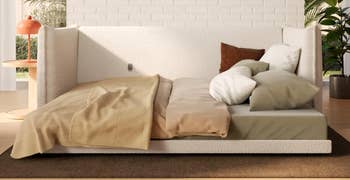Modern furniture setup with assorted pillows and a textured blanket, acceptable successful a cozy, natural-light-filled country with potted plants and a stylish lamp