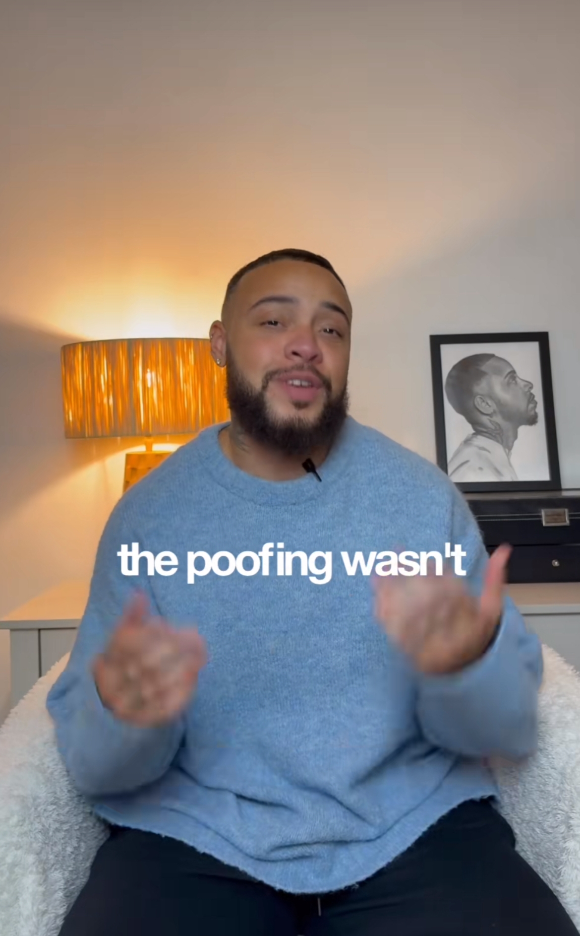 Person som sitter i et koselig rom og gestikulerer mens han snakker. Et innrammet portrett er på bordet i bakgrunnen. Teksten på skjermen lyder: "the poofing wasn'n"