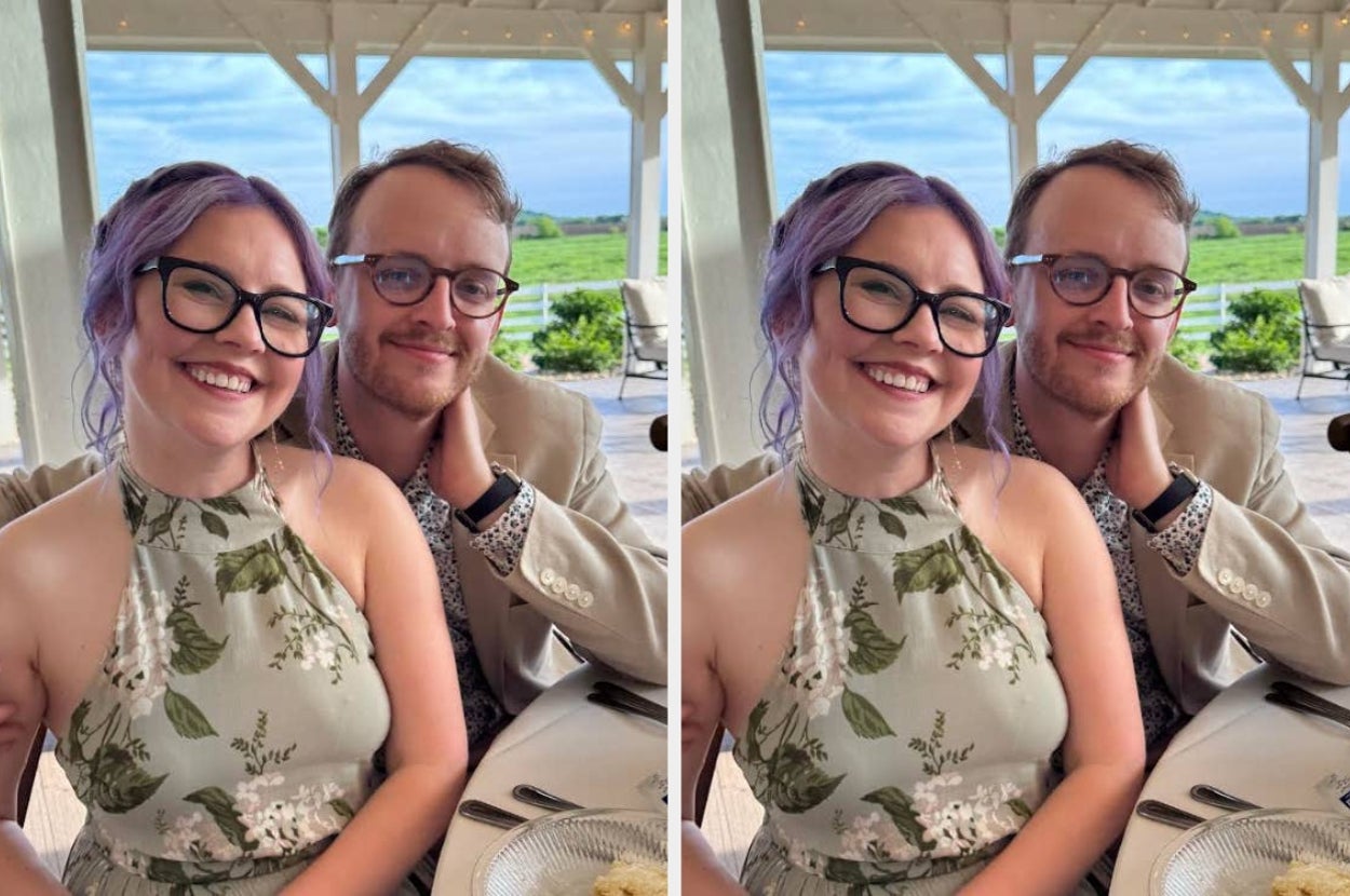 Two people smiling at a table outdoors. The woman wears a floral halter dress, and the man has glasses and a beige blazer