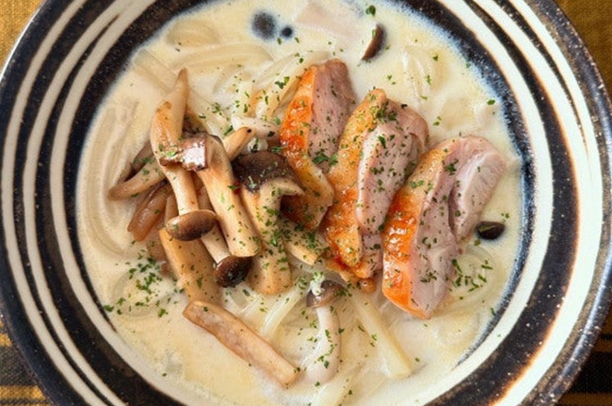 クリーミーなパスタの上に、スライスした鴨肉ときのこがトッピングされた料理。パセリが散らされています。