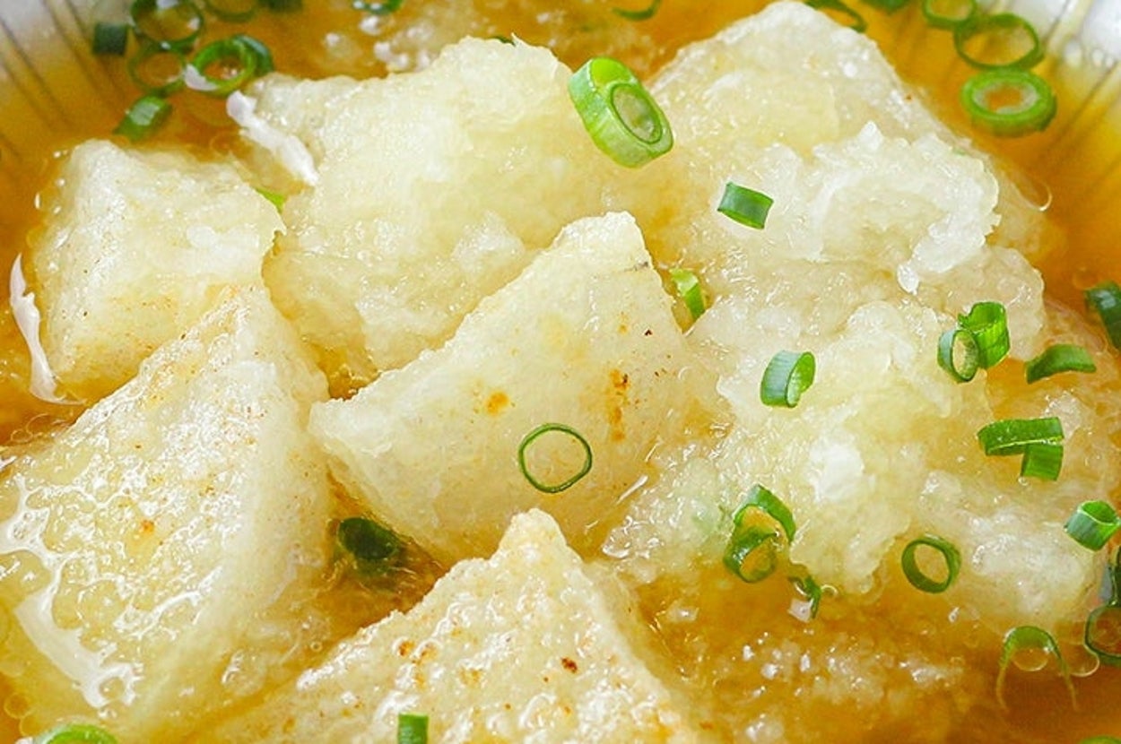 大根おろしと揚げ出し豆腐が出汁に浸され、ネギが散らされた料理。