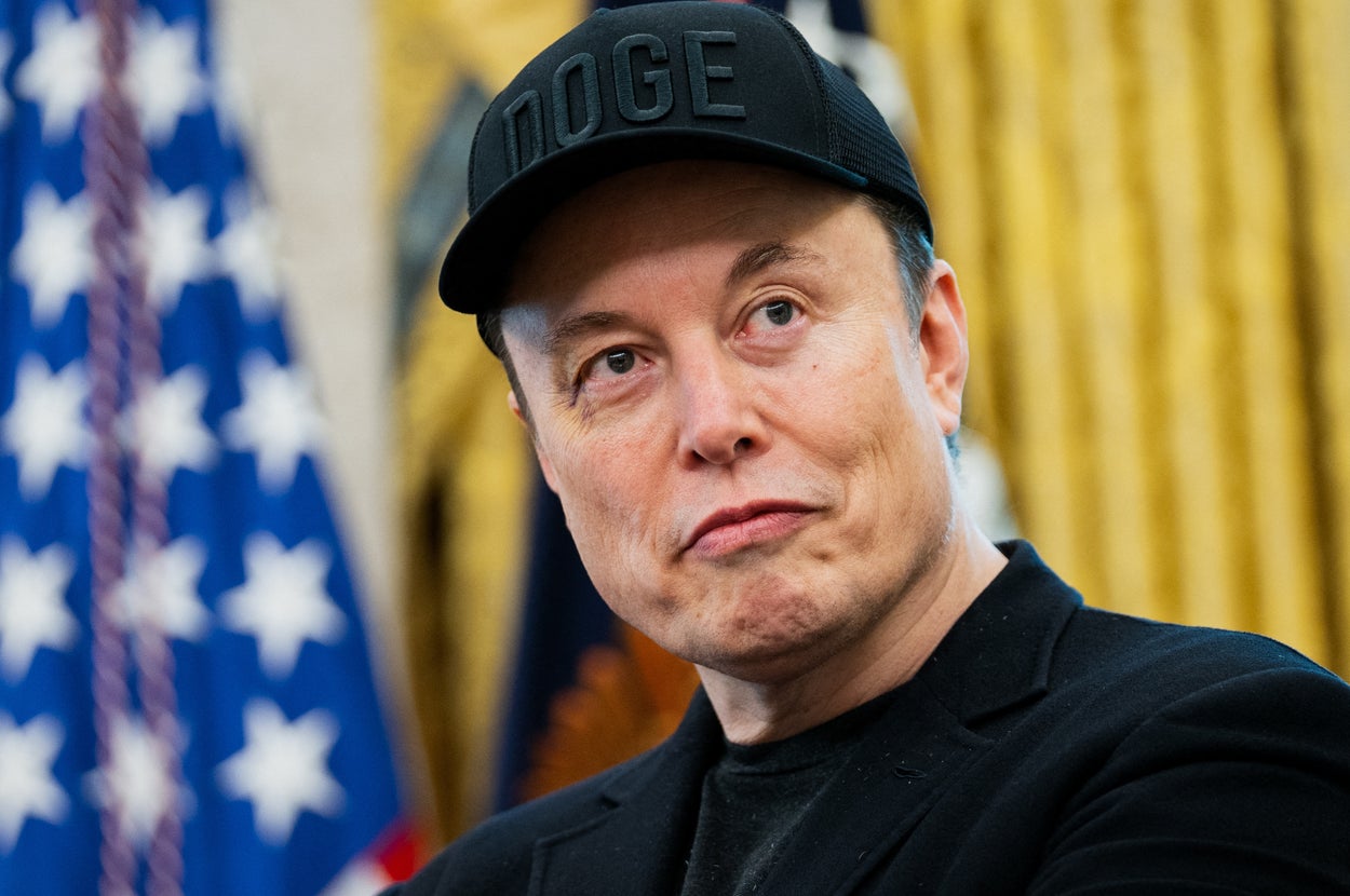 人物がキャップをかぶり、真剣な表情で見上げている。背景に旗が見える。