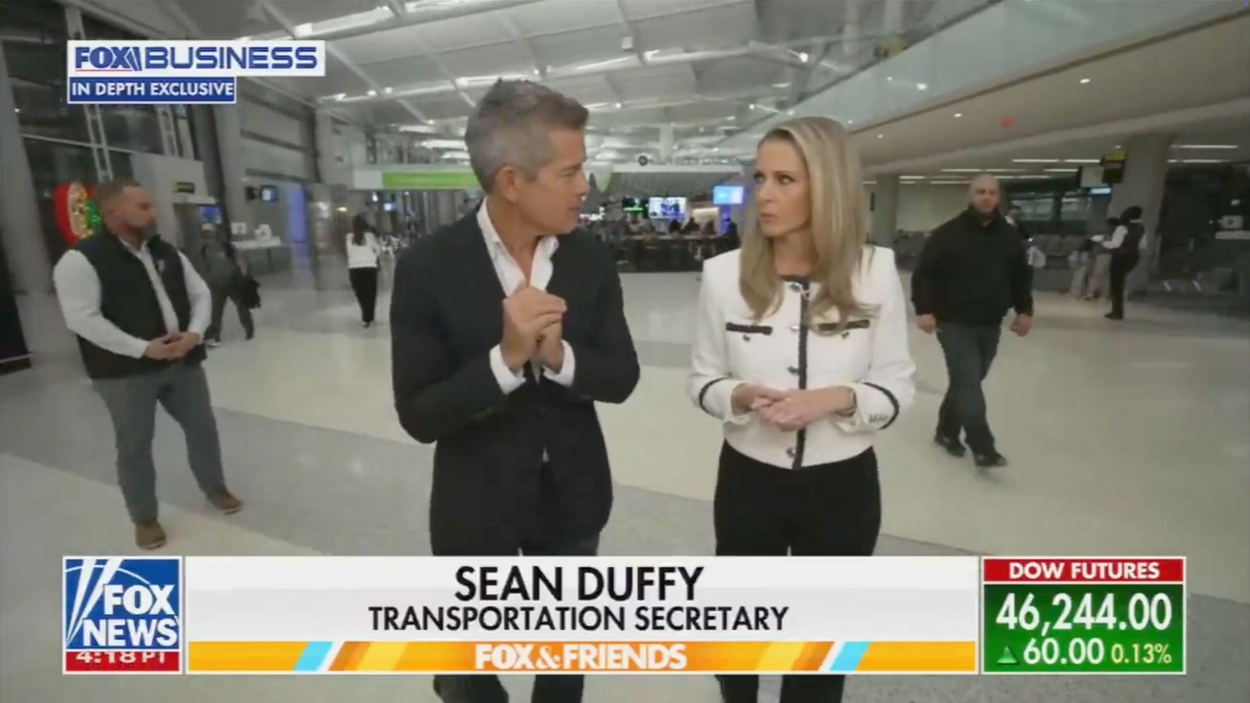 Two people, 1  successful  a suit   and 1  successful  a nonrecreational  outfit, are walking and talking successful  an airport. News ticker displays &quot;Sean Duffy, Transportation Secretary.&quot;