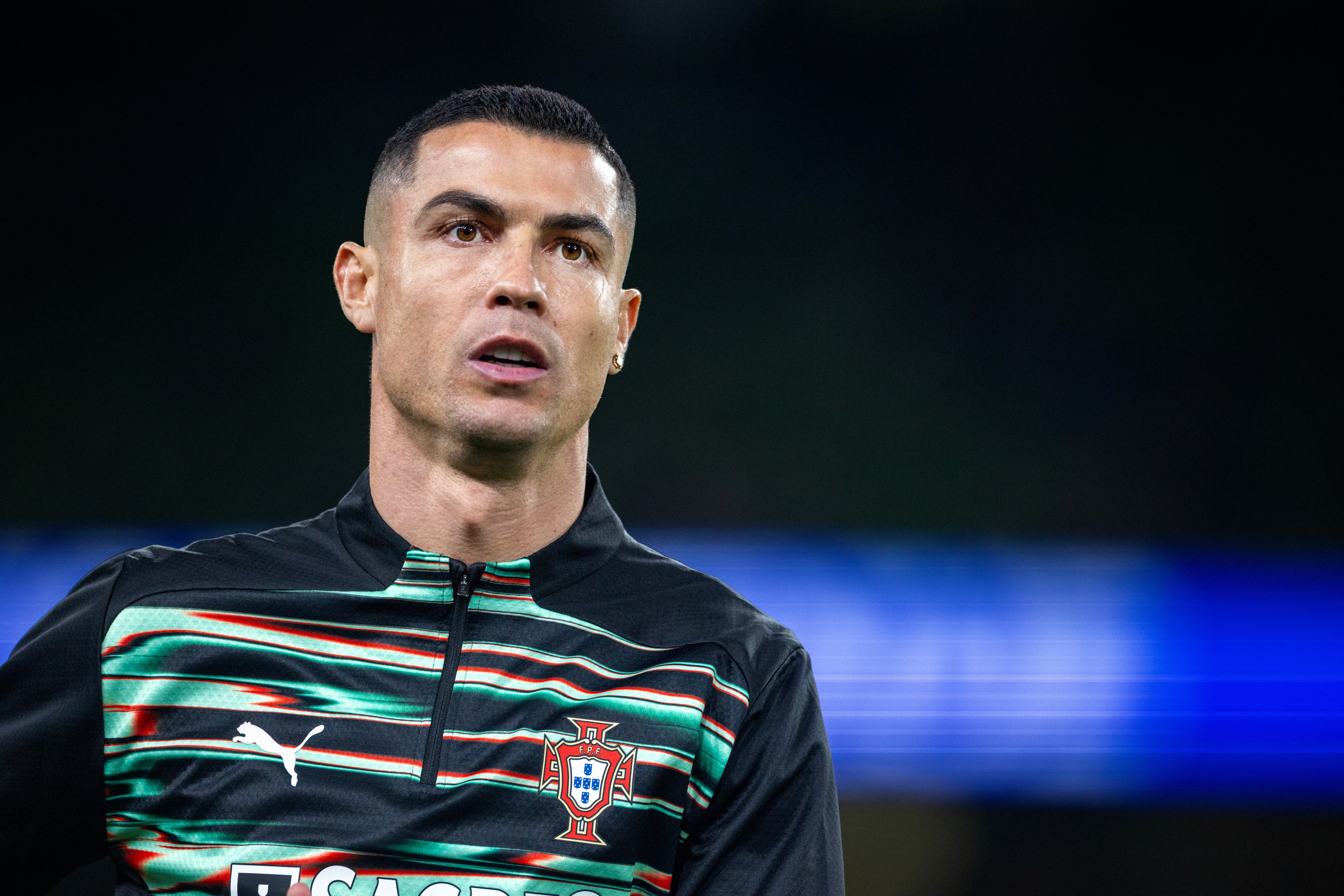 A shot subordinate with abbreviated hairsbreadth is wearing a sports overgarment featuring stripes and the nationalist emblem, looking towards the side