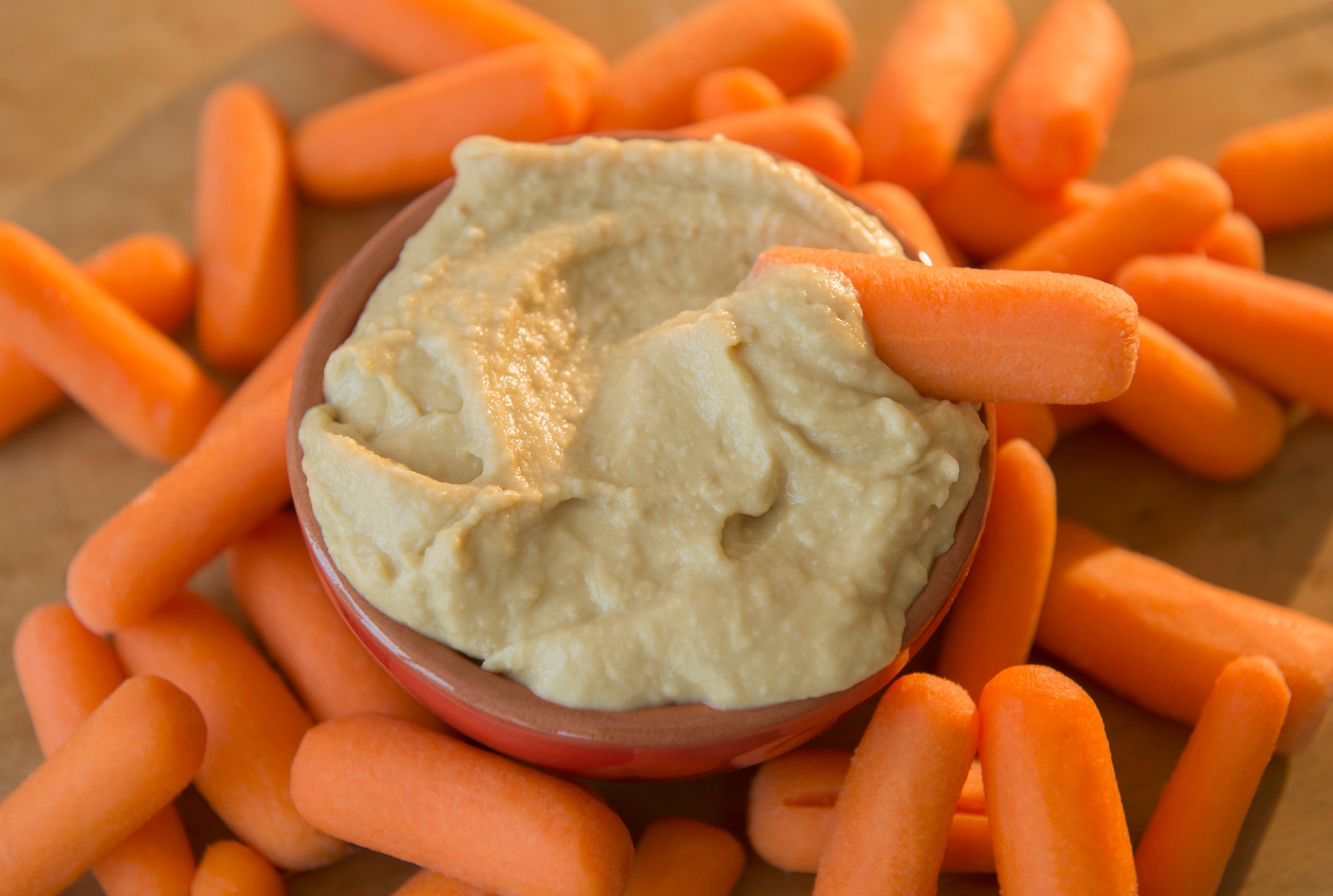 Bowl of hummus surrounded by babe  carrots, with 1  carrot dipped successful  the hummus