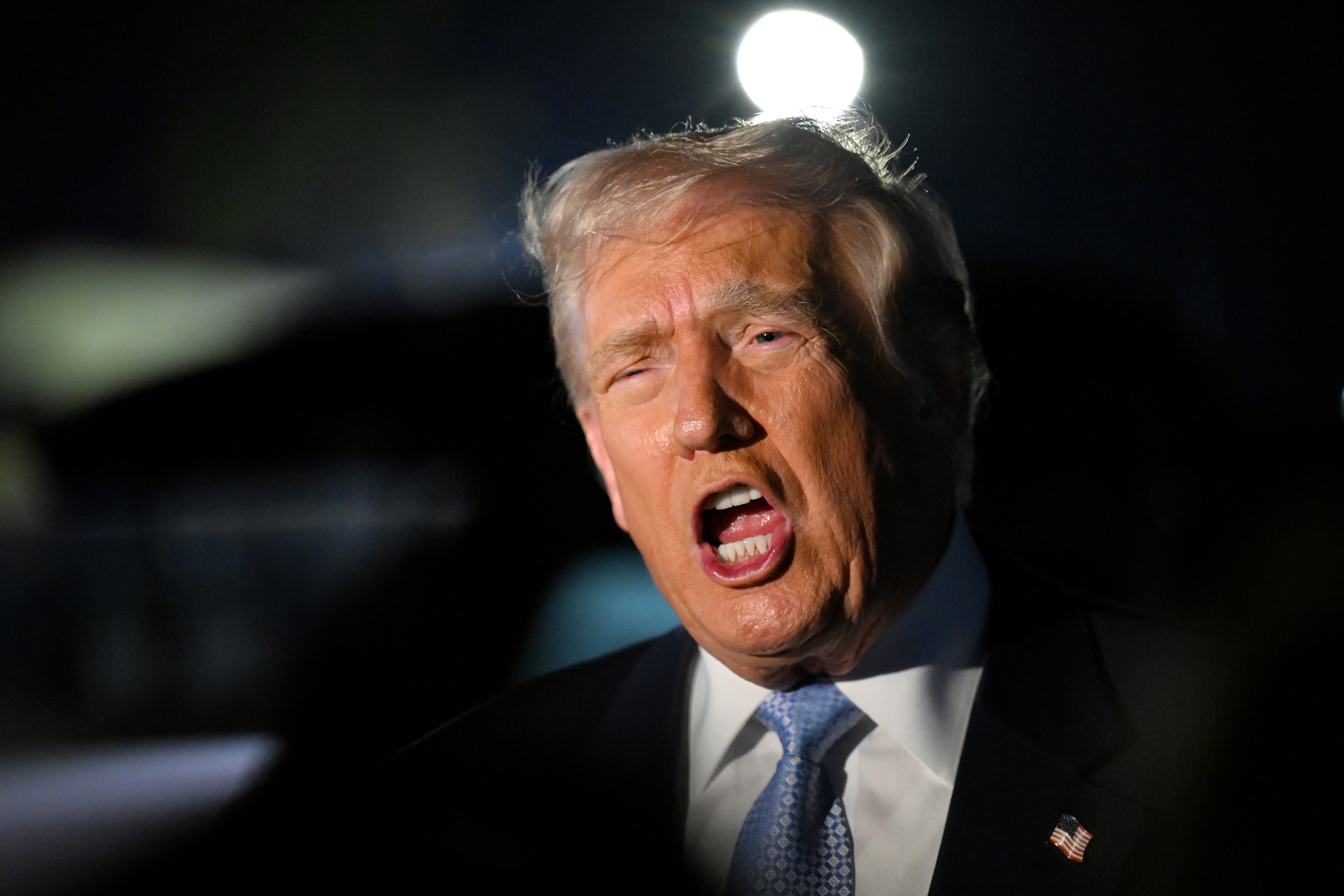 Man successful a suit speaking passionately astatine a nighttime event, with agleam lights successful the background