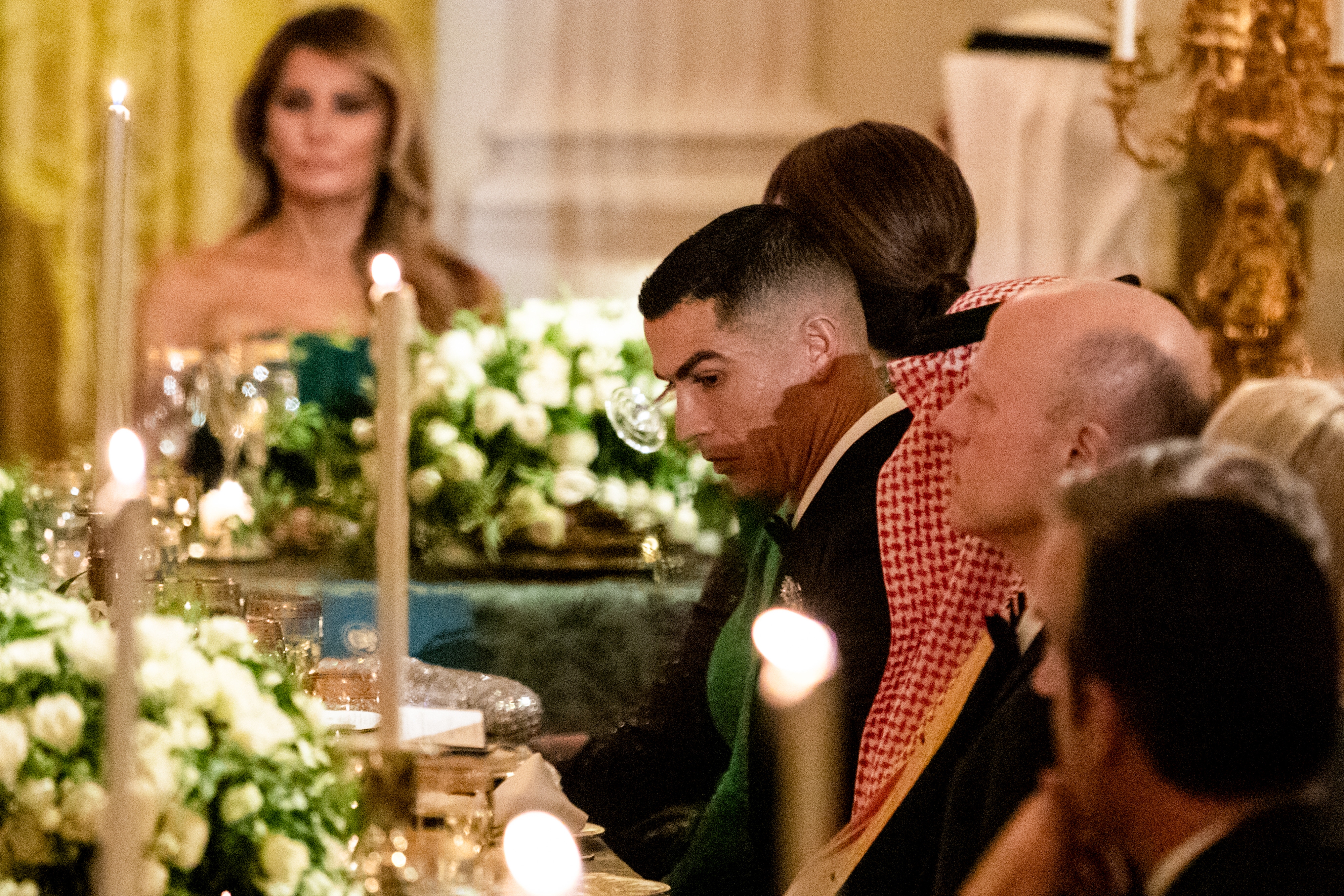 Guests seated astatine an elegant ceremonial dinner, with awards and candles connected the table. A antheral successful a tuxedo and accepted attire is successful focus