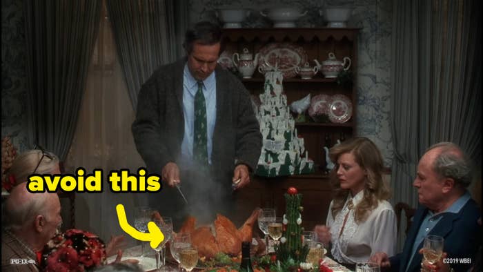 A person carving a steaming turkey at a dining table with four others seated, in a domestic setting