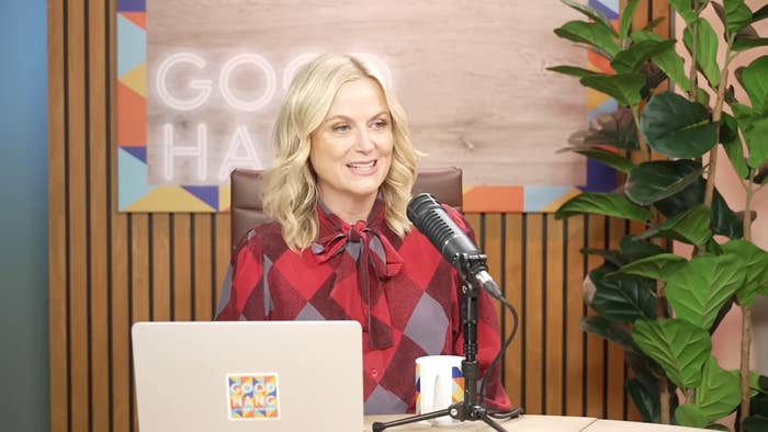 Person seated astatine  a podcast setup, wearing a patterned formal  with a bow. They&#x27;re speaking into a microphone, laptop disposable   successful  front