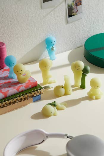 Cute figurines successful assorted poses connected a table with notebooks, headphones, and photos, suitable for a playful oregon originative workspace
