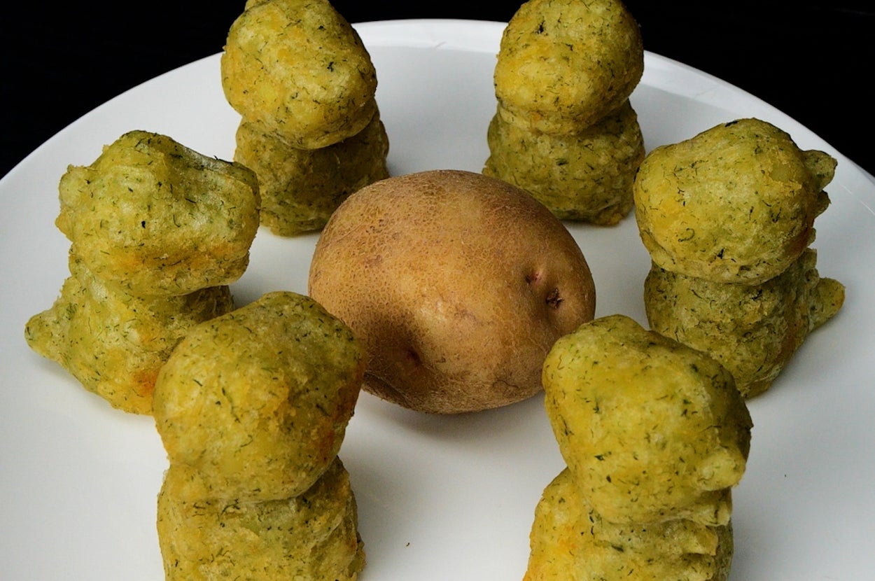 お皿の上にポテトと野菜フライが6つ並んでいる。中心に丸ごとのじゃがいもが置かれている。