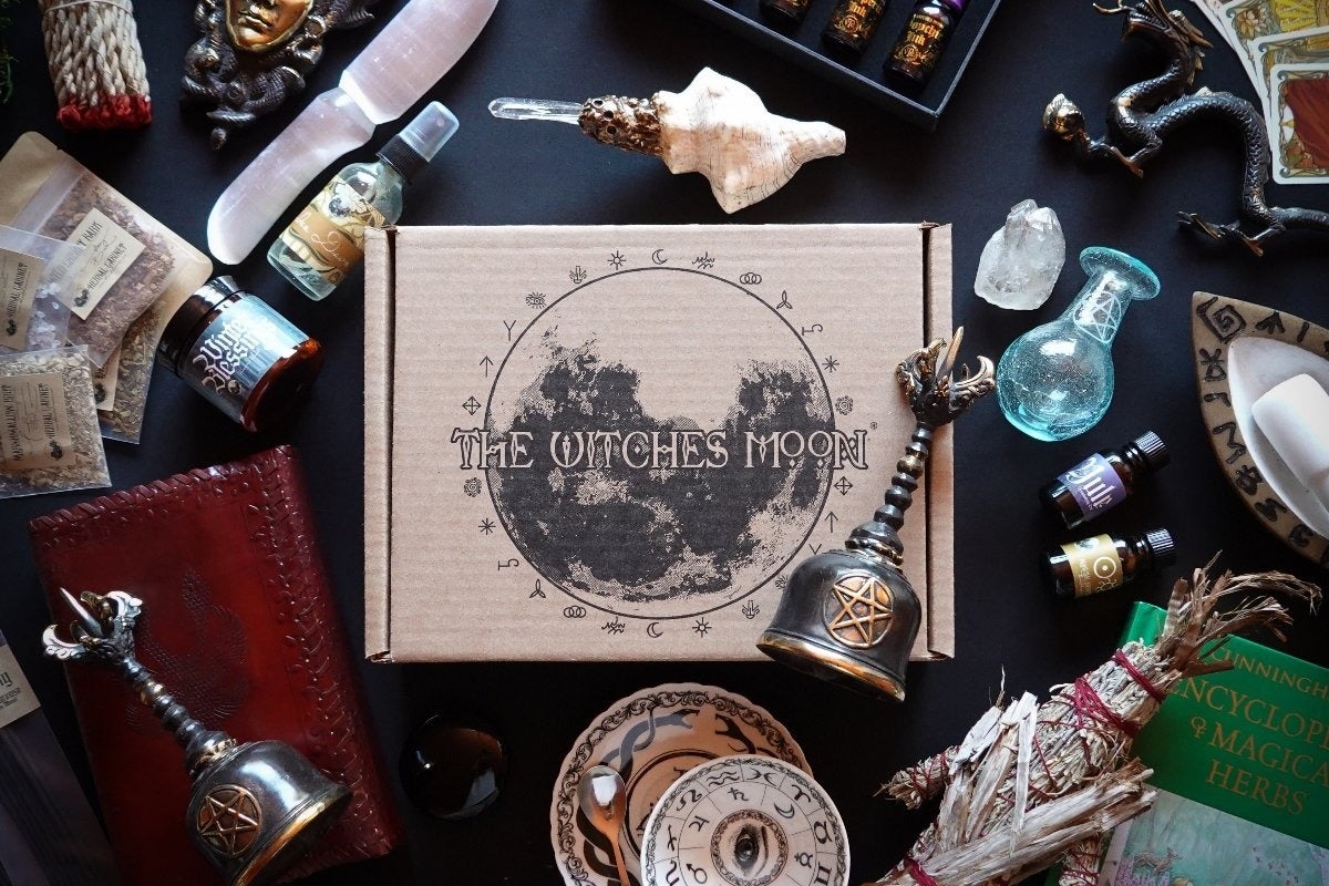 Witchcraft-themed subscription box surrounded by mystical items, including candles, crystals, and herbs, suggesting a curated magical shopping experience