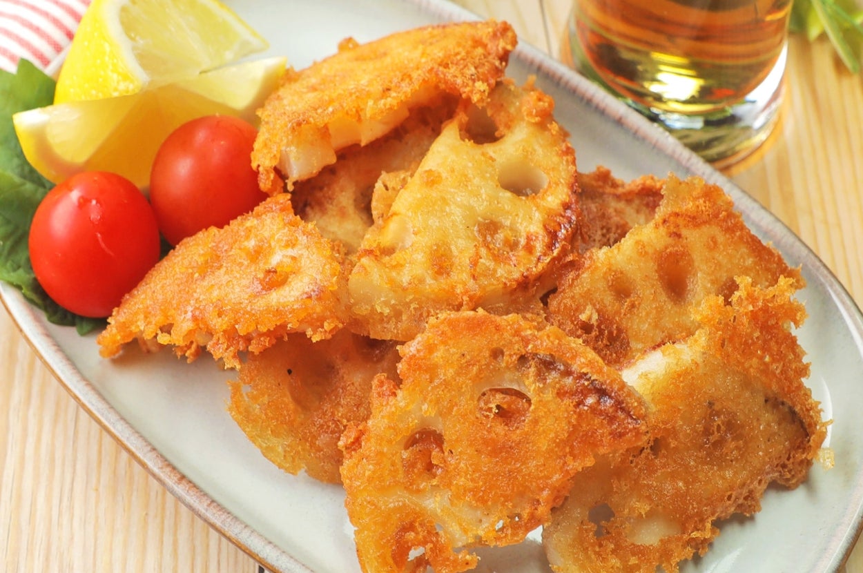 蓮根の唐揚げとレモン、ミニトマトが盛られたプレート。奥には冷たい飲み物があります。