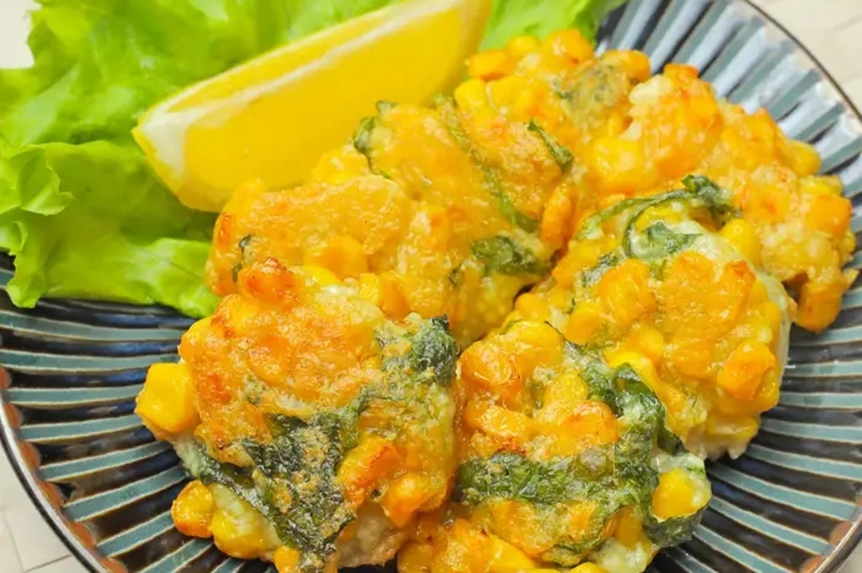 皿に盛られた豆腐ととうもろこしの料理。レタスとレモン付き。