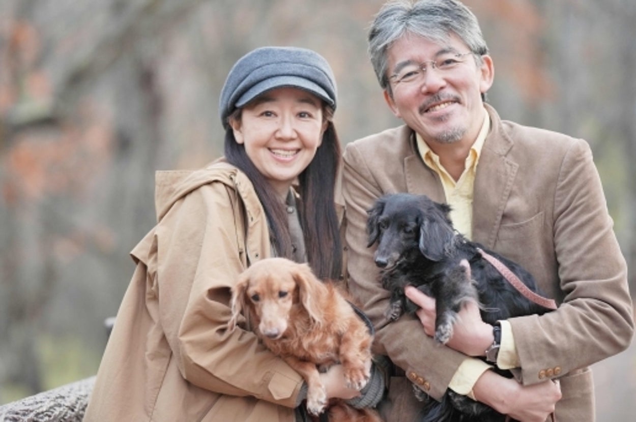 犬を抱く夫婦（写真ACより）