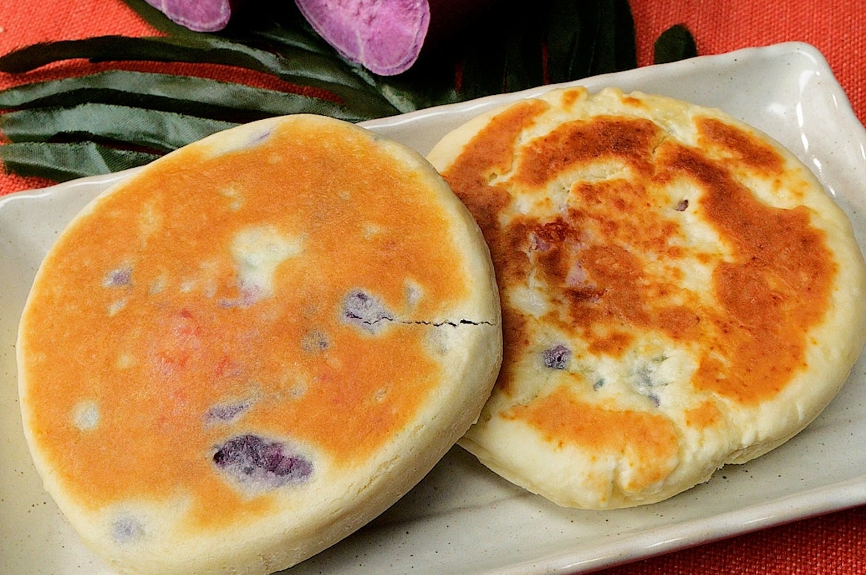 お皿に紫芋のホットケーキ2枚と、その奥にカットされた紫芋がある。