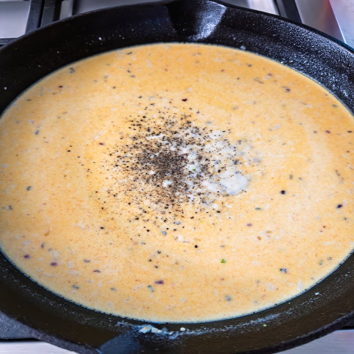 Creamy sauce in a pan with black pepper and herbs on top