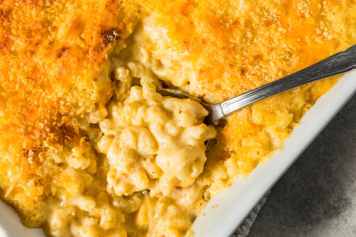 Creamy baked mac and cheese in a dish, with a spoon scooping a portion