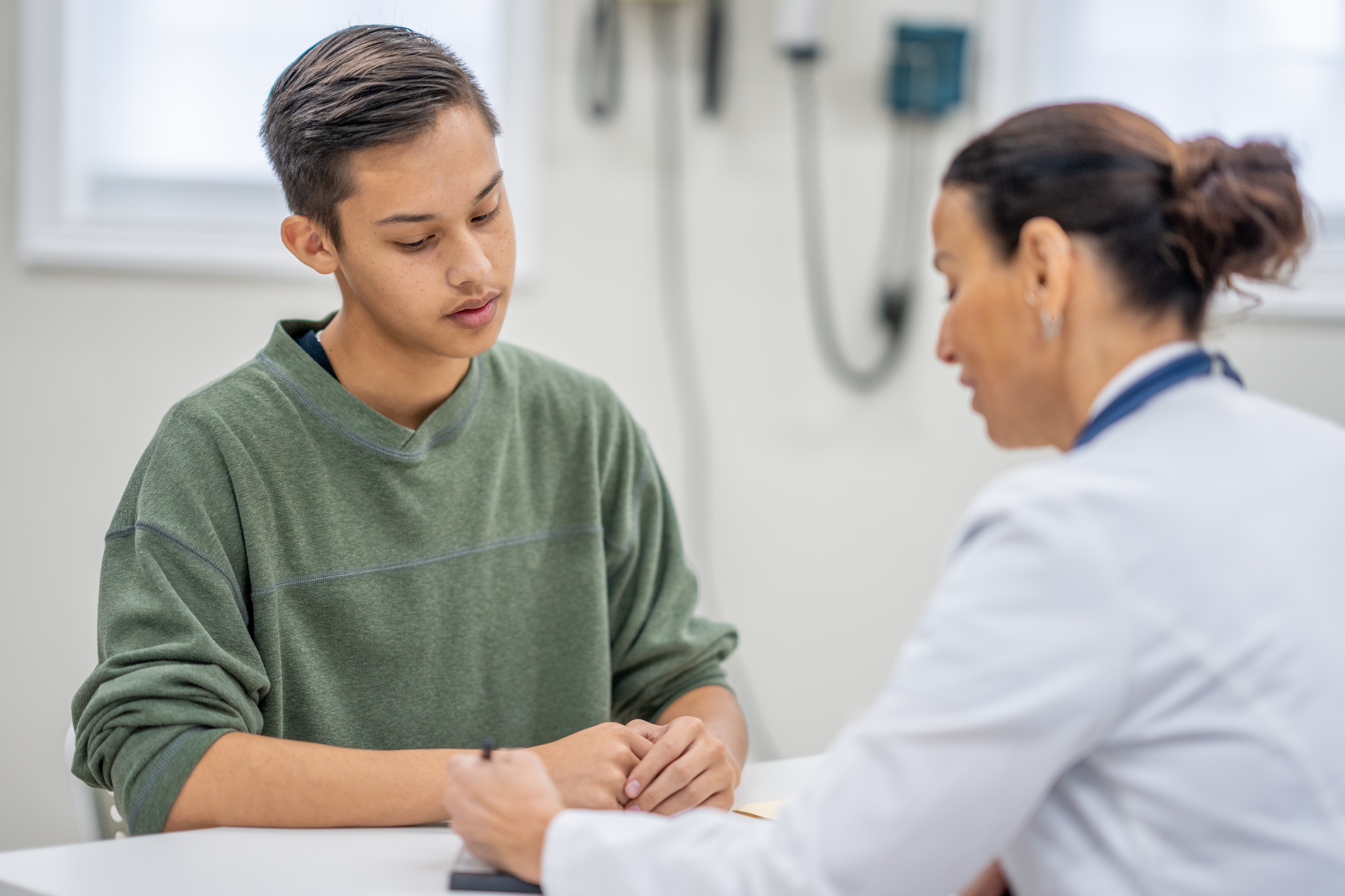 Lege og ung pasient har en samtale ved en medisinsk kontorpult