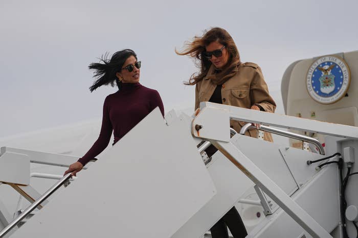 Two women in stylish outfits descend stairs from a plane, engaged in conversation