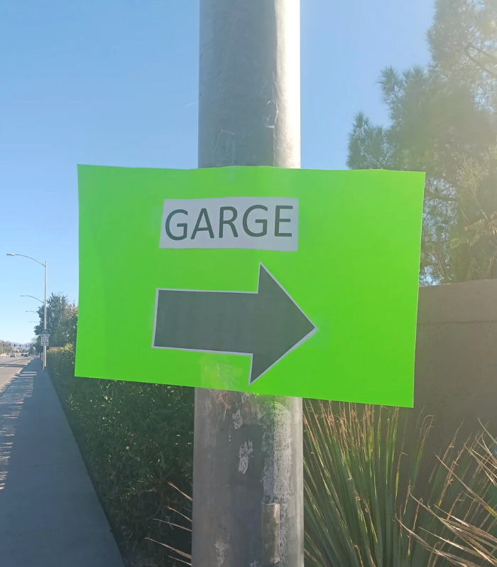 Sign connected  a rod  with "Garge" and a ample  arrow pointing right, perchance  a misspelling of "garage." Located connected  a sunny street