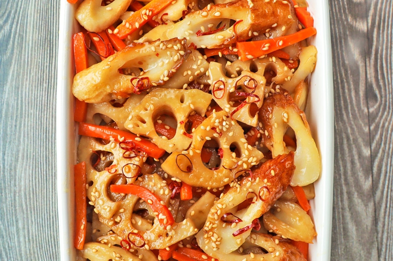 レンコンとニンジンの炒め物が白い皿に盛られ、ごまが振りかけられています。