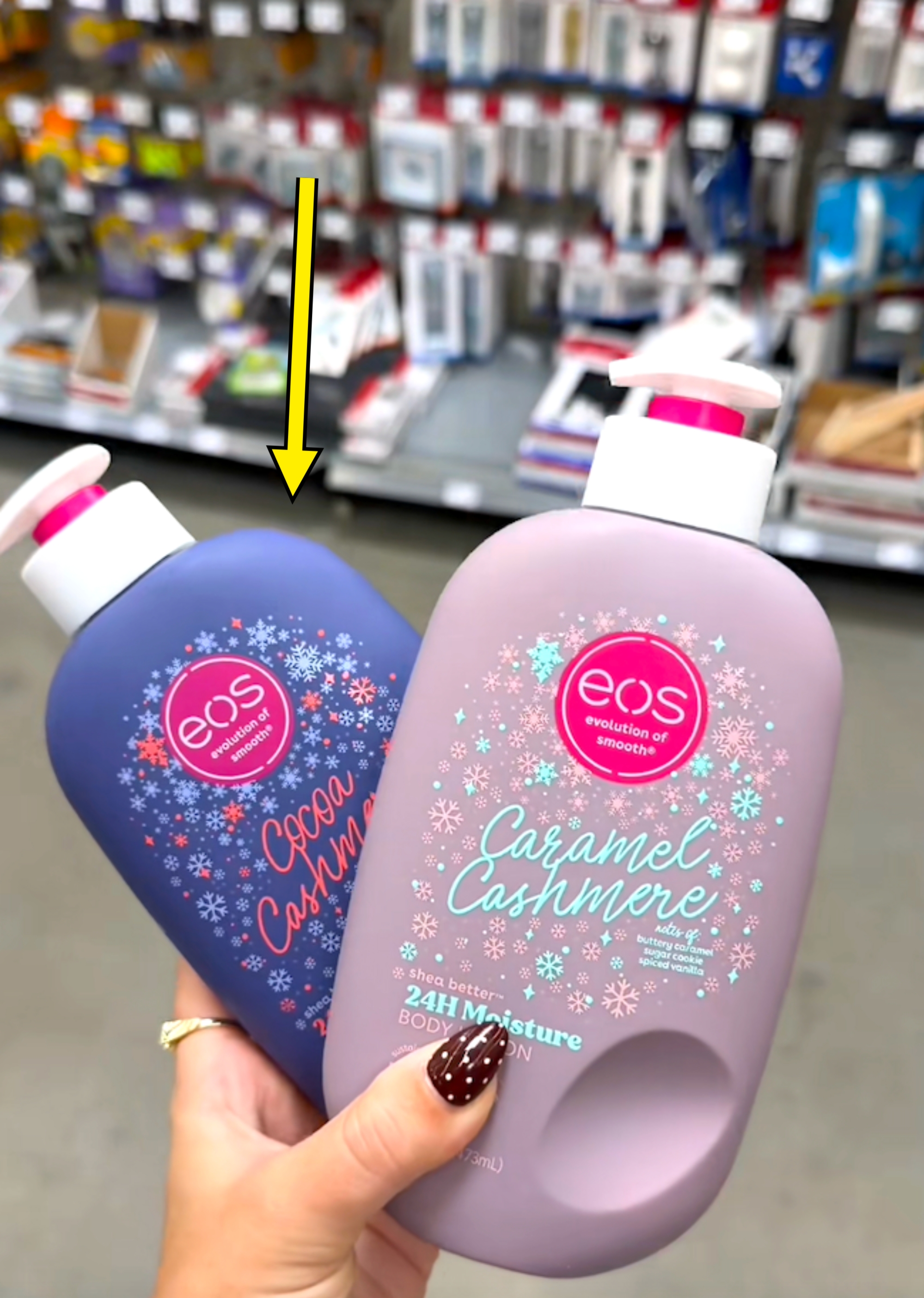 Two EOS body lotions, "Cocoa Cashmere" and "Caramel Cashmere," held in a store aisle with office supplies in the background