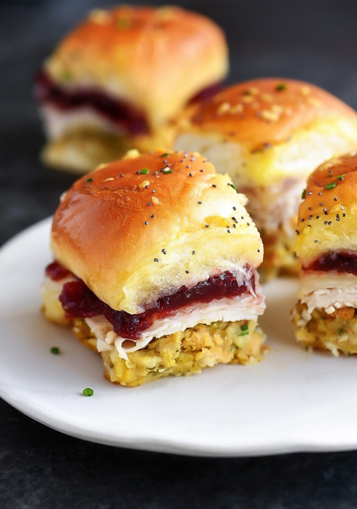Small sandwiches with turkey, stuffing, and cranberry sauce on a white plate