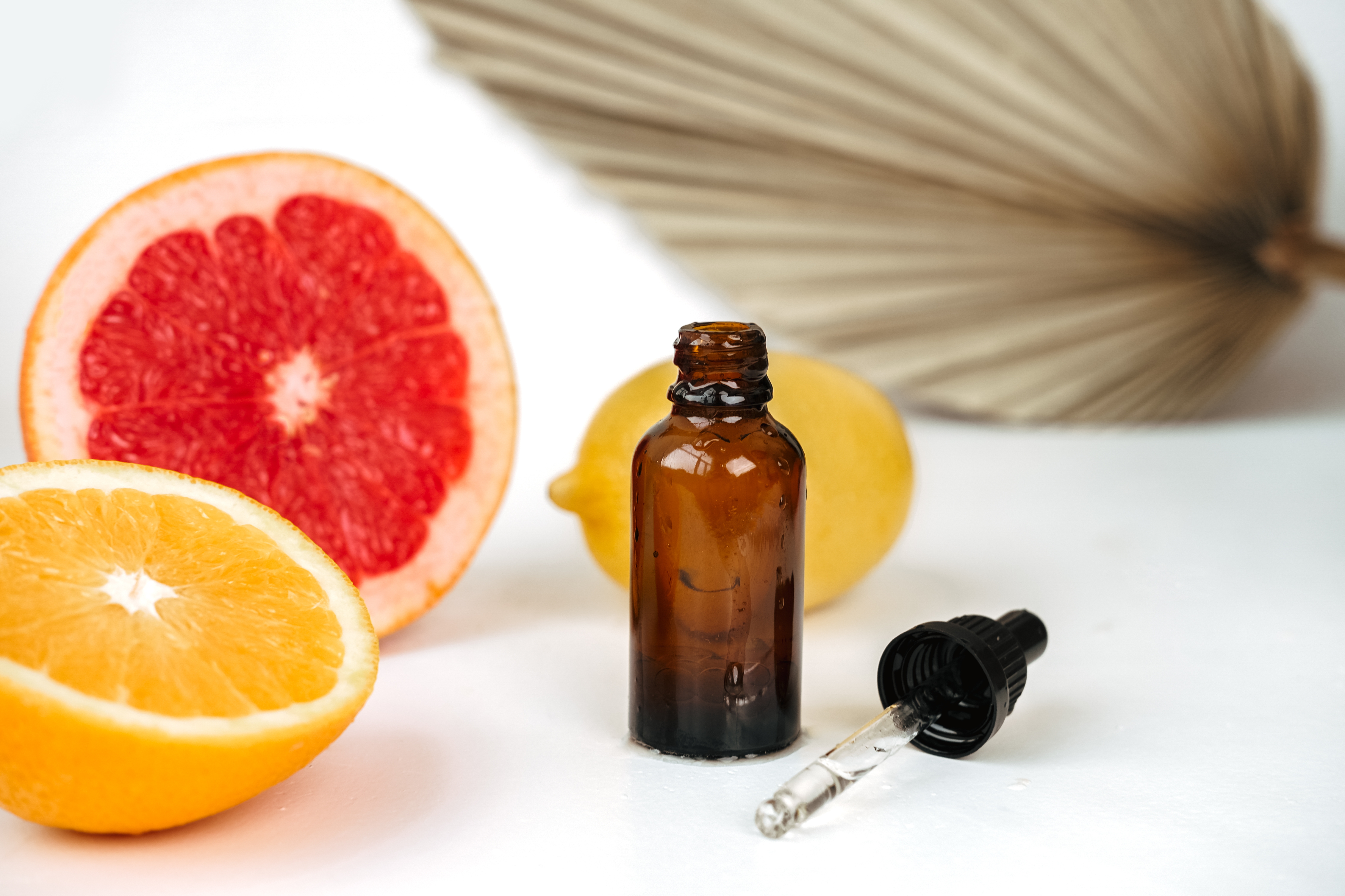Dråpeflaske med sitrusfrukter og blader, som foreslår naturlig hudpleie eller aromaterapi i en velværefokusert setting