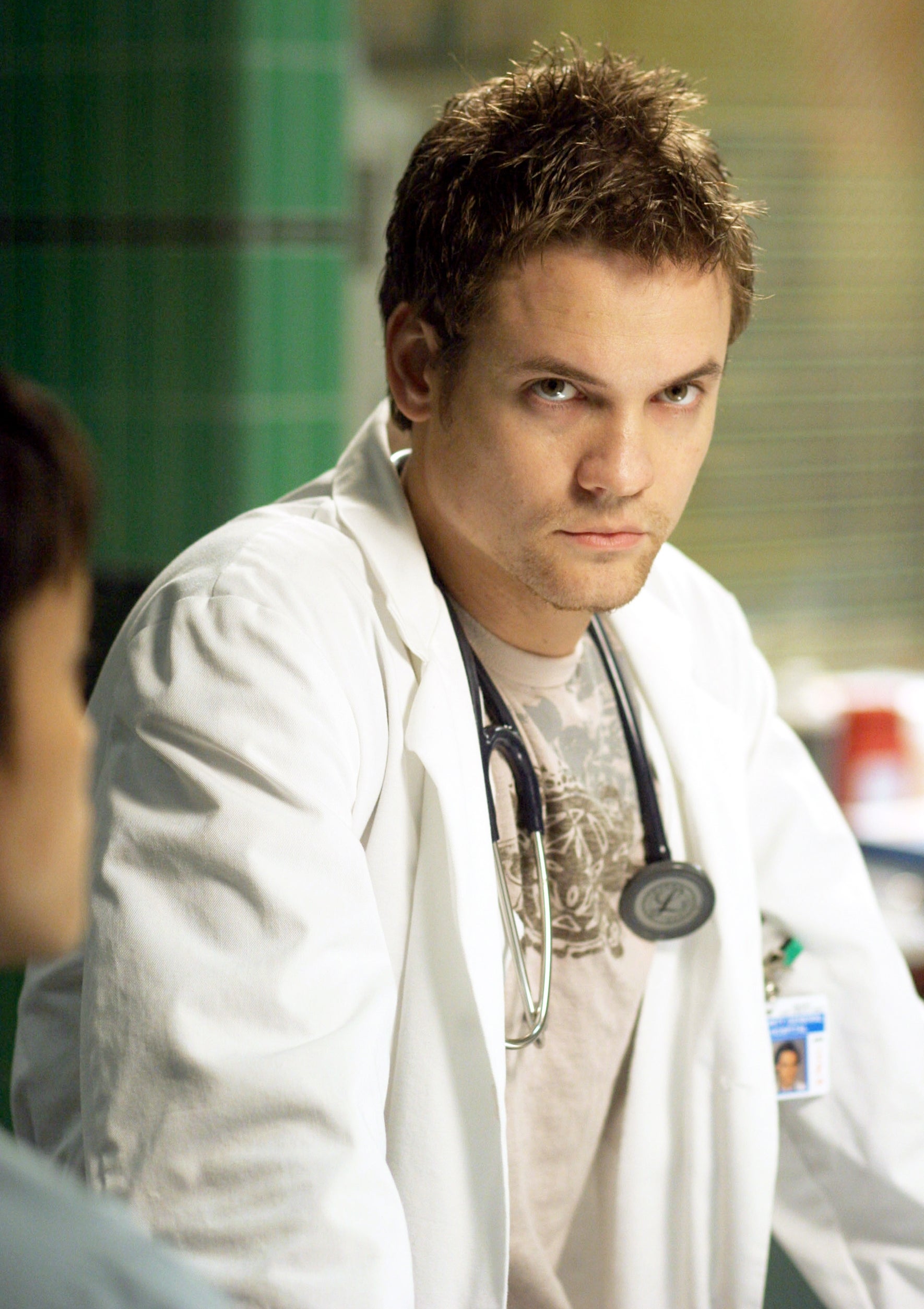 A man wearing a white lab coat and graphic tee