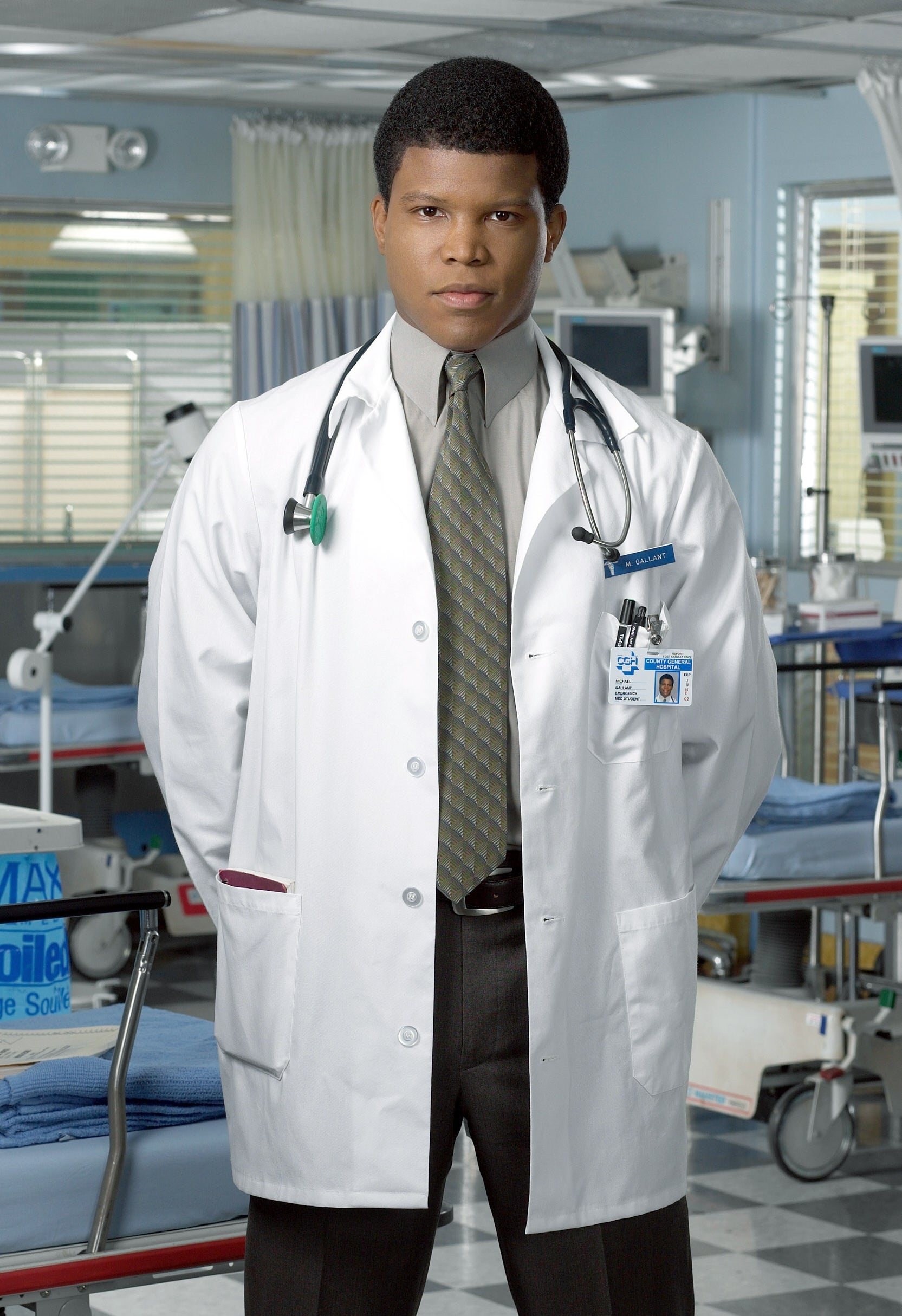 A man wearing a white lab coat, tie, and, and trousers in a medical setting