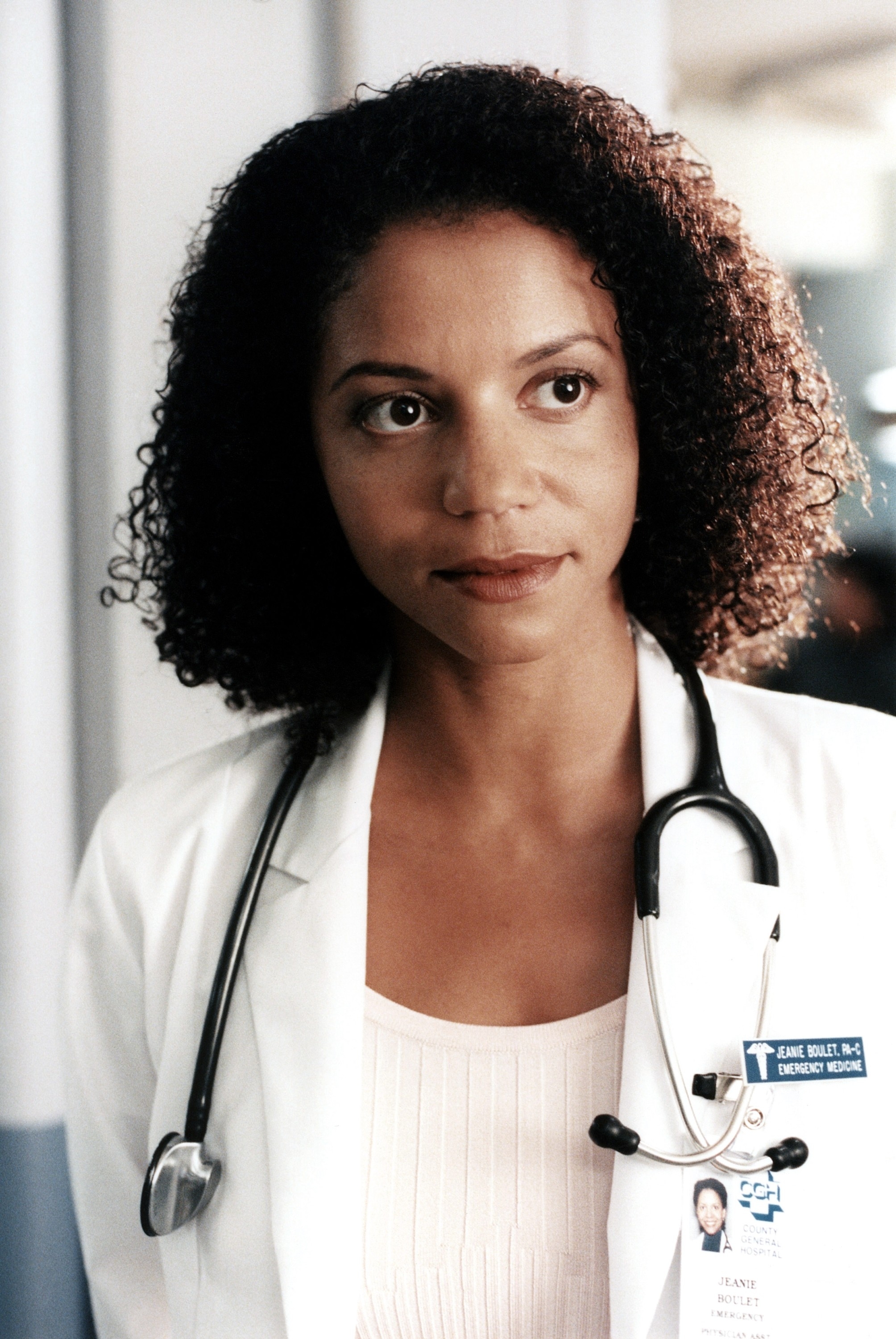 A woman wearing a white lab coat with medical accessories around her neck