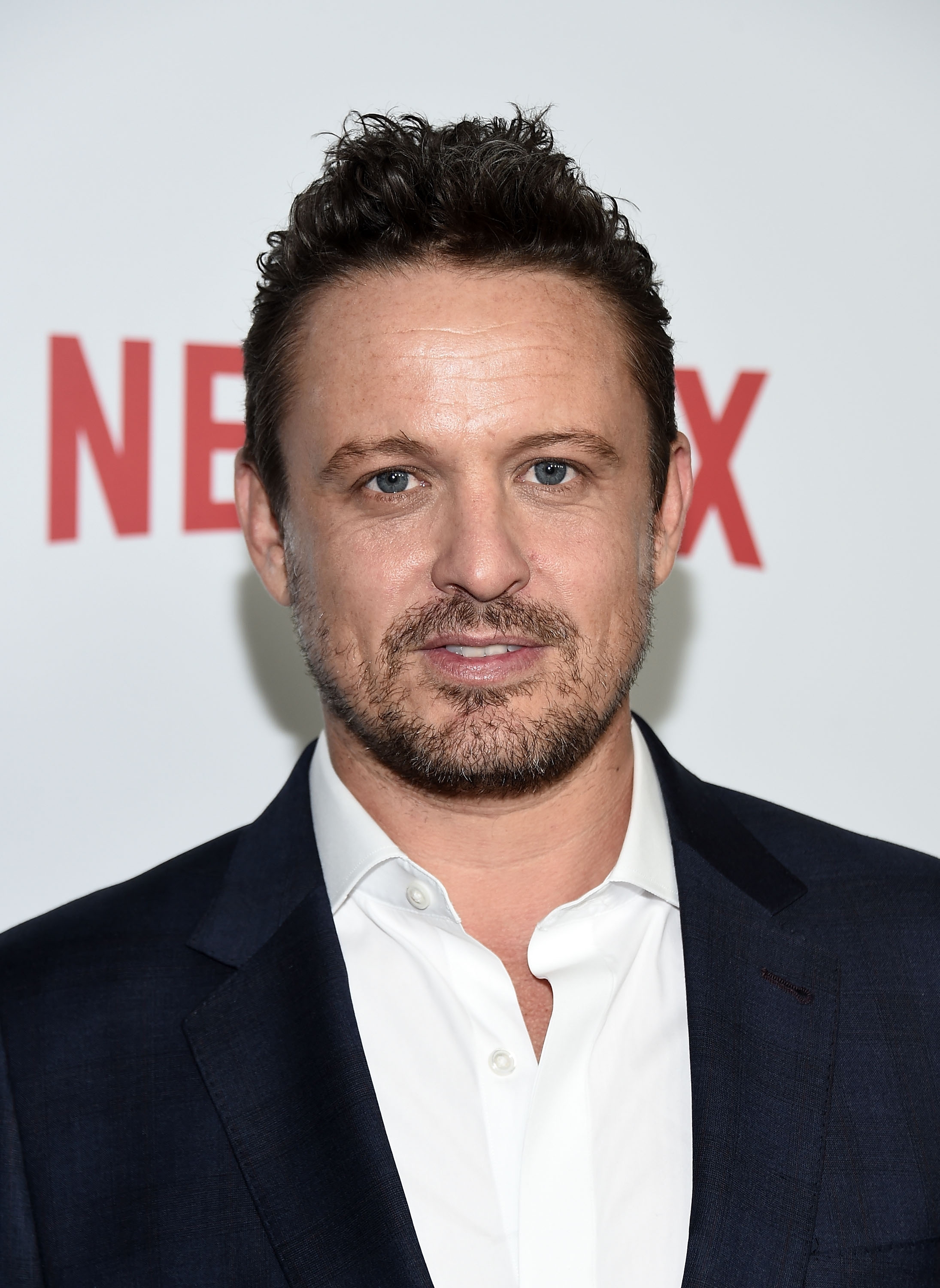 A man wearing a white button-up shirt and suit jacket