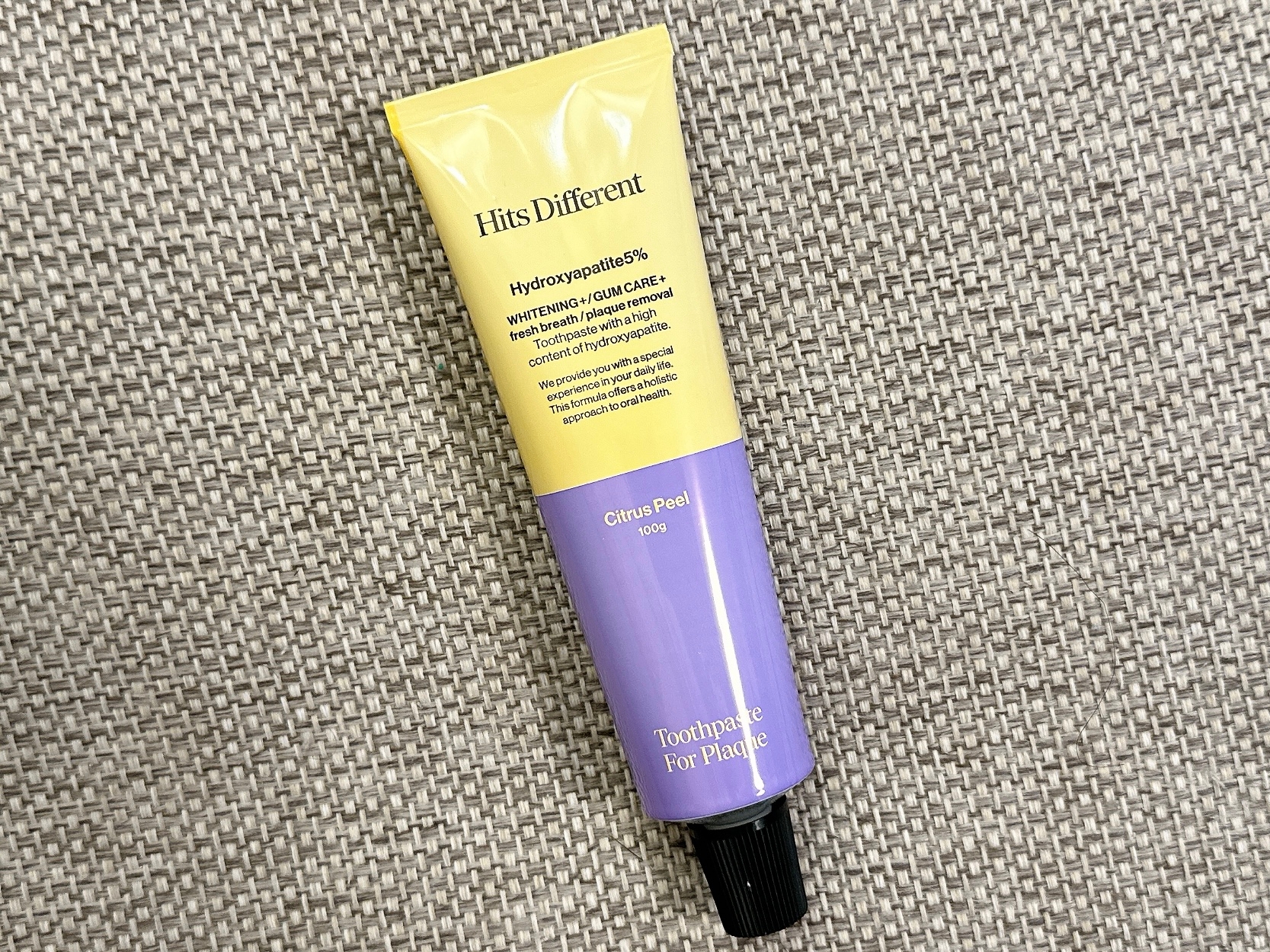 テクスチャ付き背景に置かれた歯磨き粉のチューブ、「Hits Different」と書かれています。