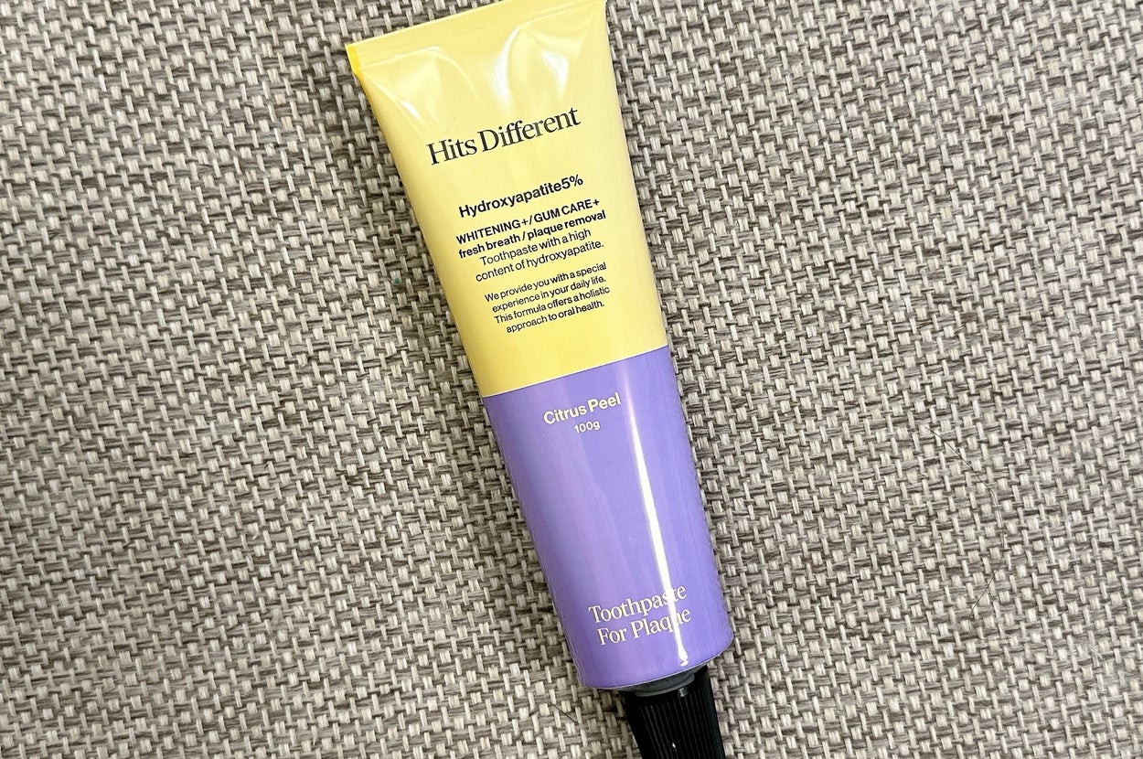 テクスチャ付き背景に置かれた歯磨き粉のチューブ、「Hits Different」と書かれています。