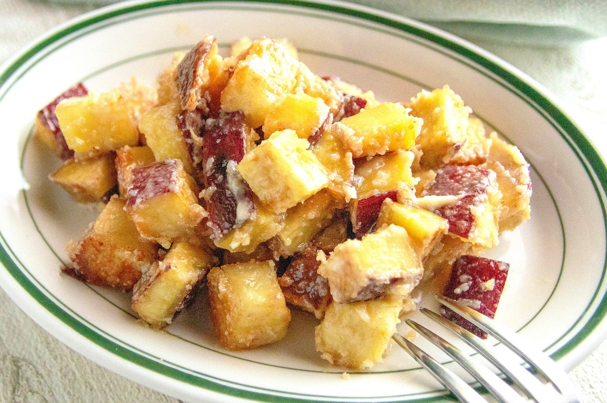 皿に盛られたキューブ状の揚げた食材は、食欲をそそる見た目です。フォークが添えられている。