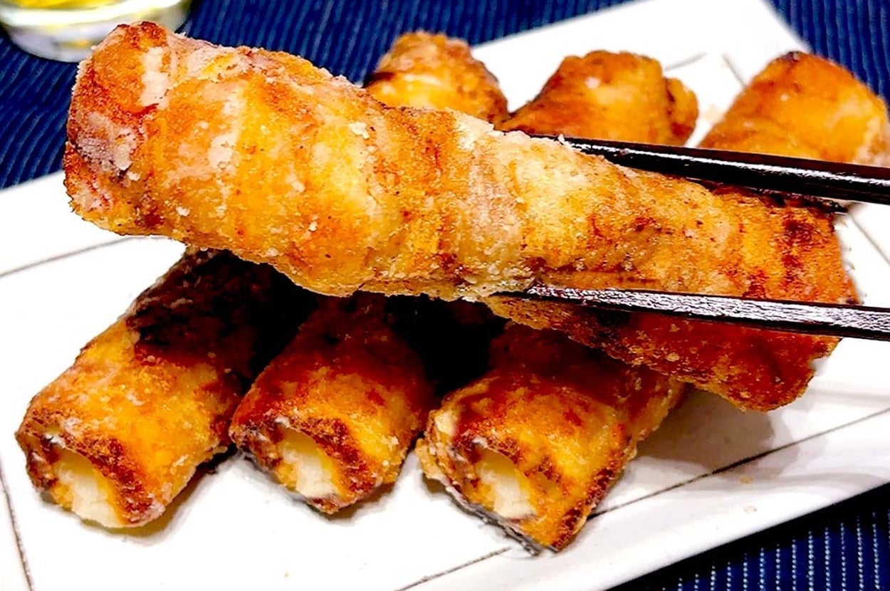 お皿に盛られた揚げた春巻きを箸で持ち上げるシーン。