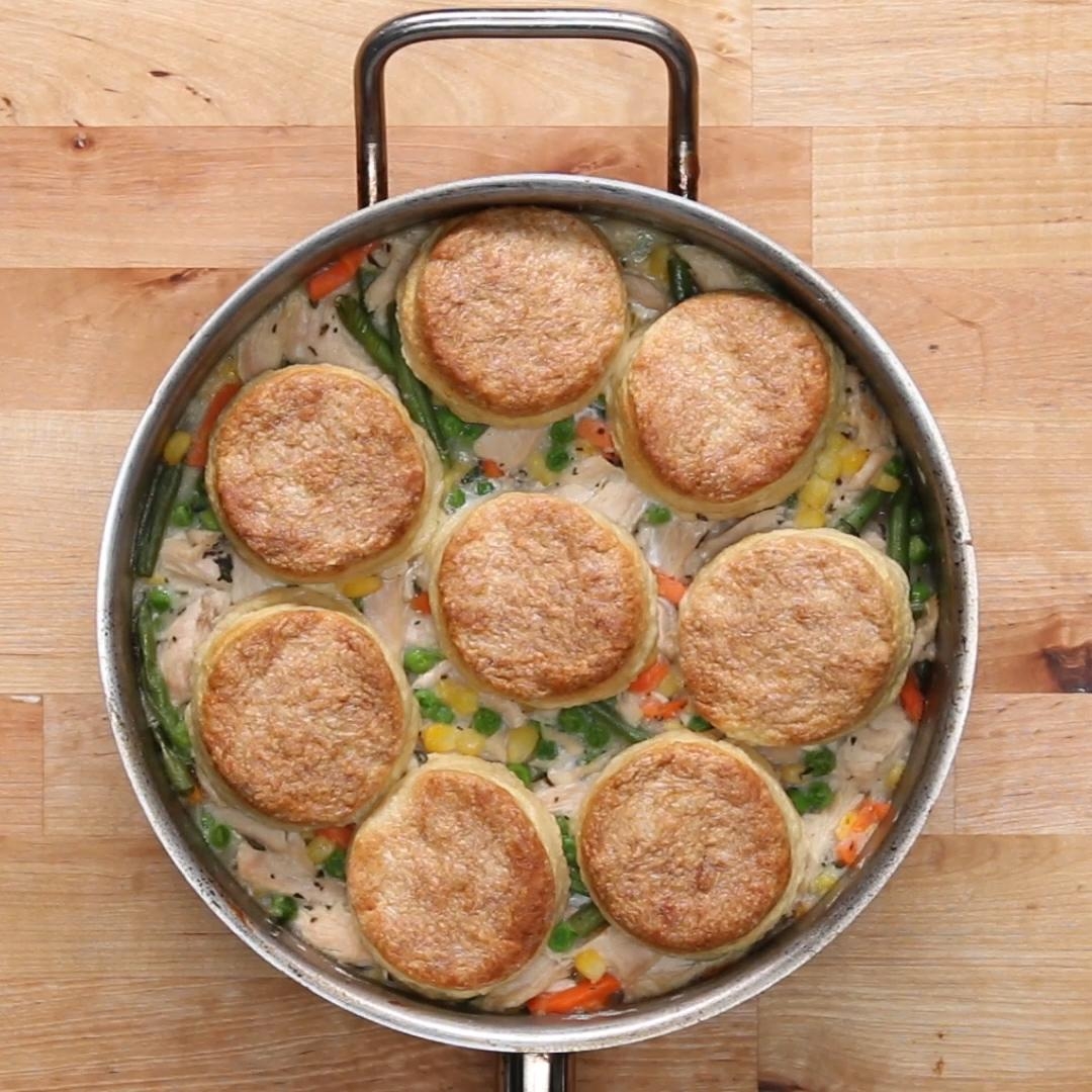 Pot pie topped with eight biscuits in a skillet, filled with creamy chicken and vegetables like green beans and carrots