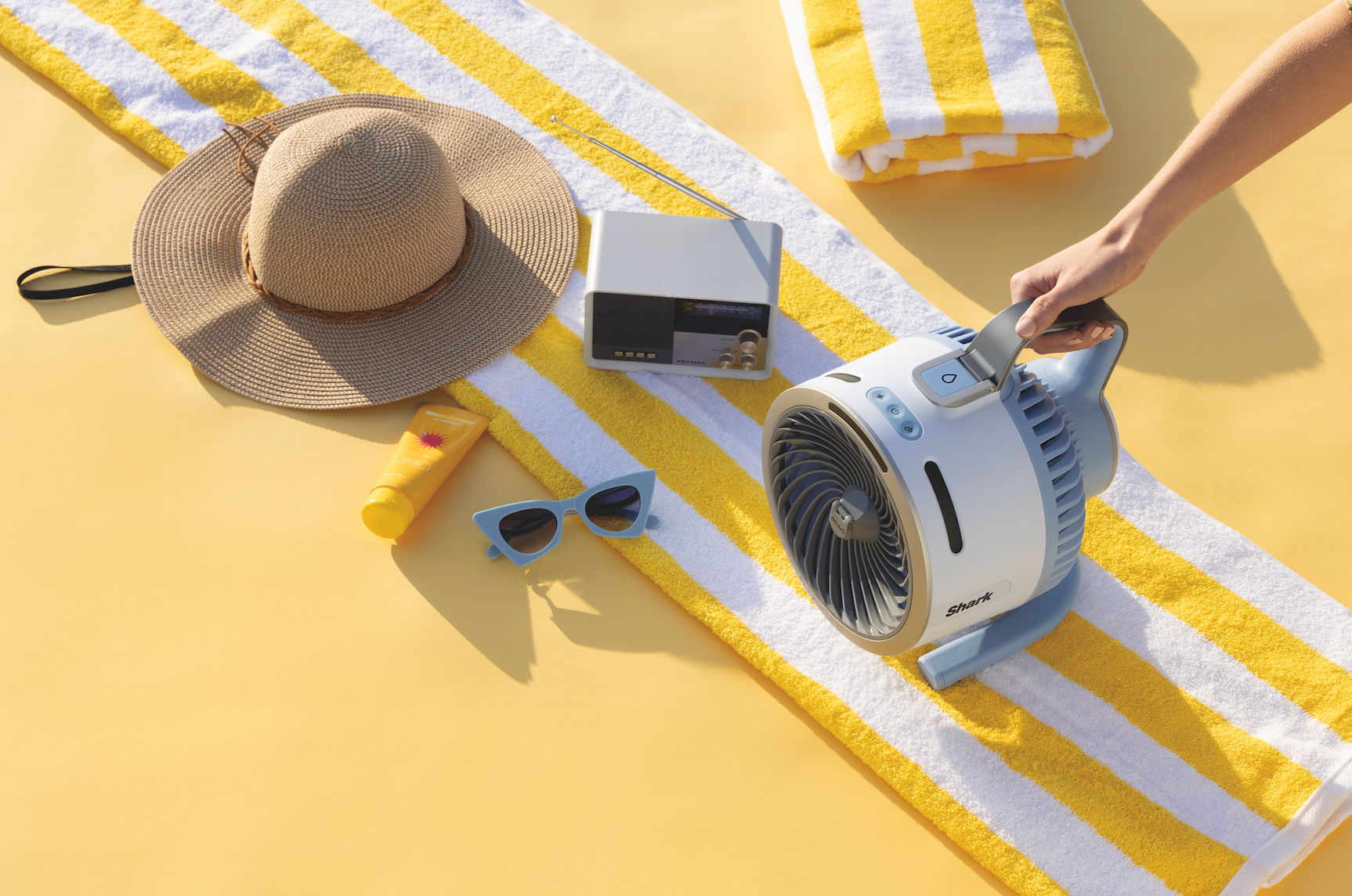 Beach essentials arranged neatly, including a straw hat, sunscreen, sunglasses, radio, striped towel, and a handheld instrumentality being carried
